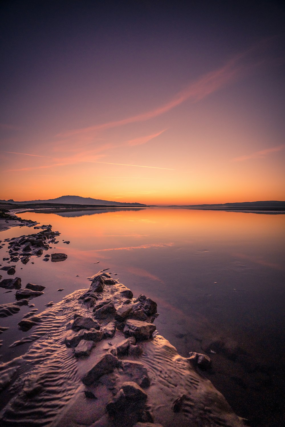 the sun is setting over the water at the beach