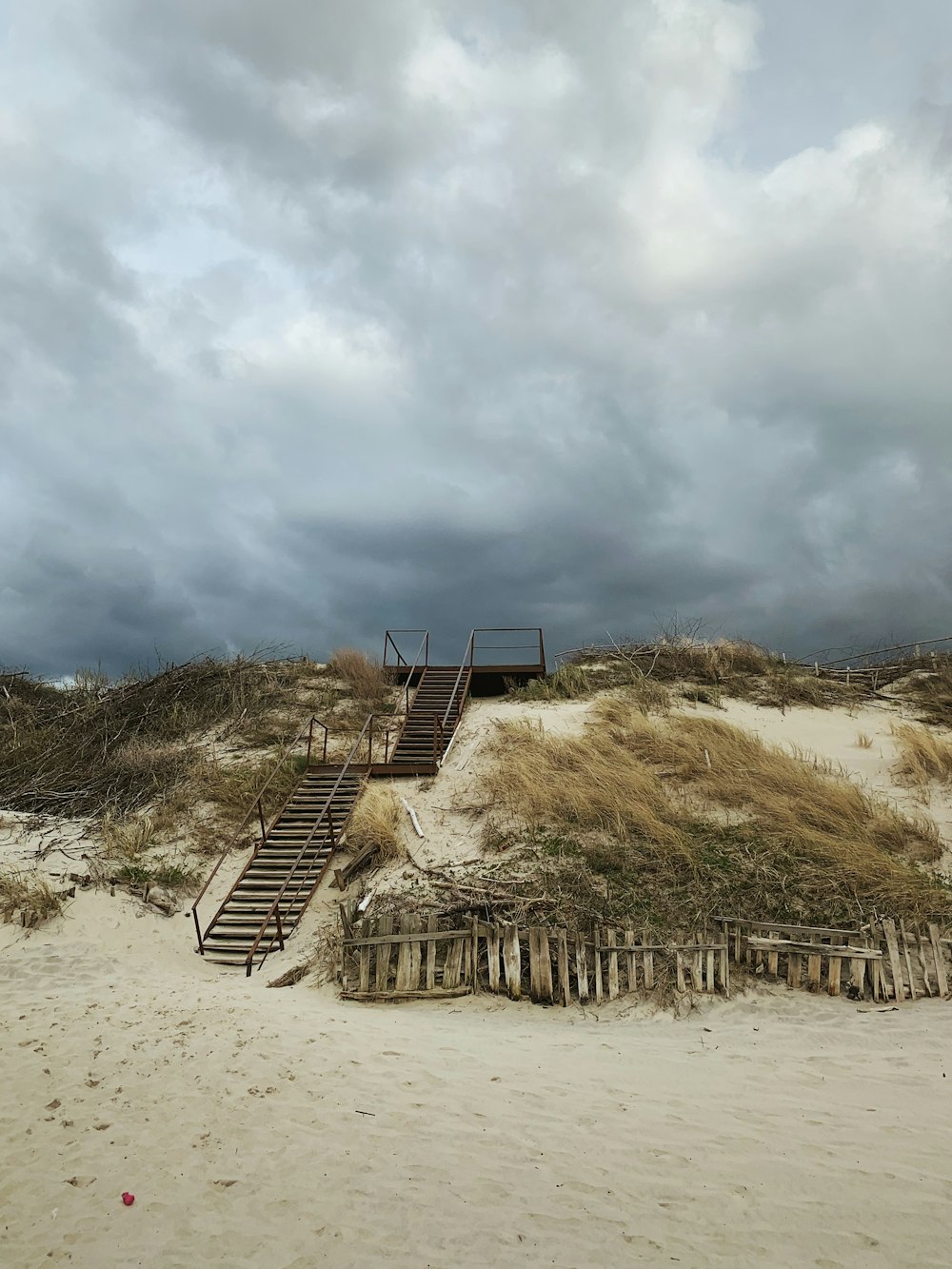 a stairway leading to a beach with a cloudy sky