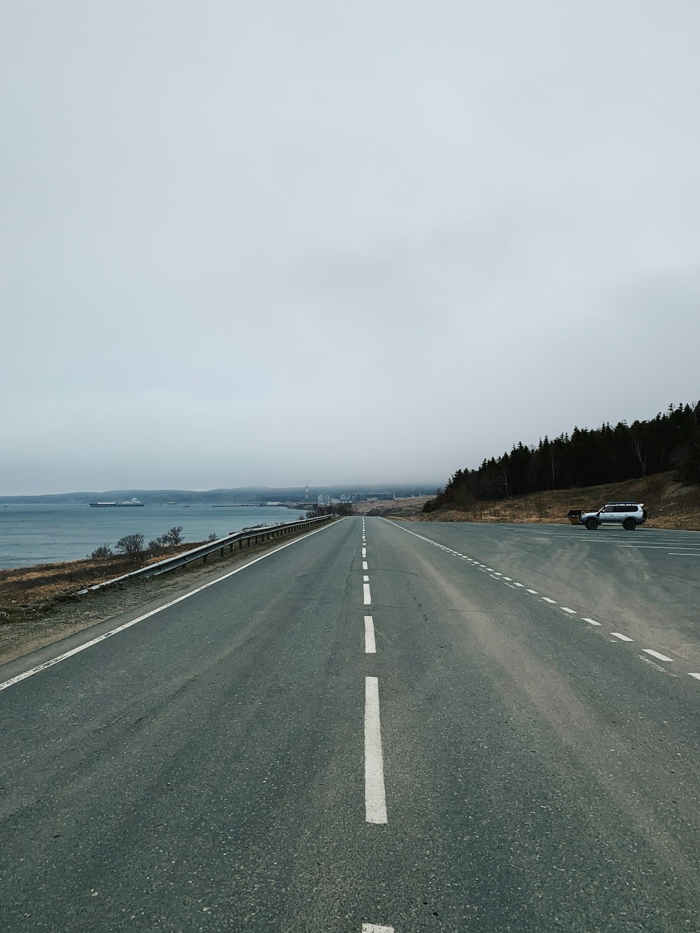 an empty highway with a car on the side of it