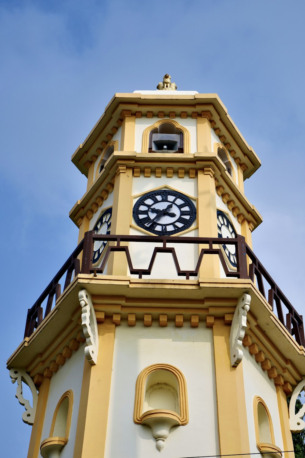 a yellow and white clock tower against a blue sky