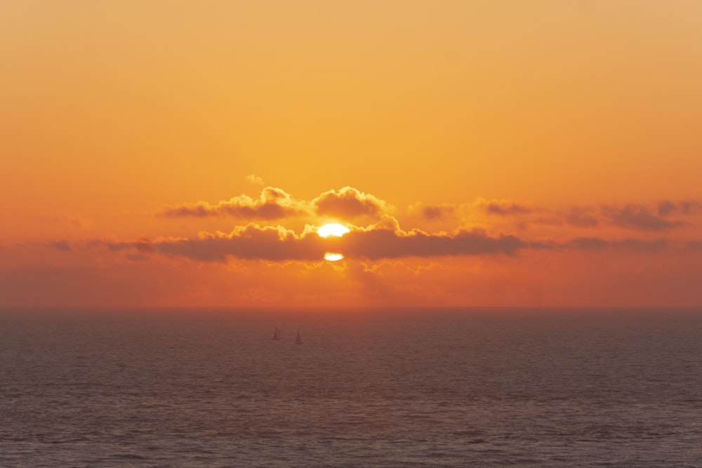 una gran masa de agua con una puesta de sol en el fondo