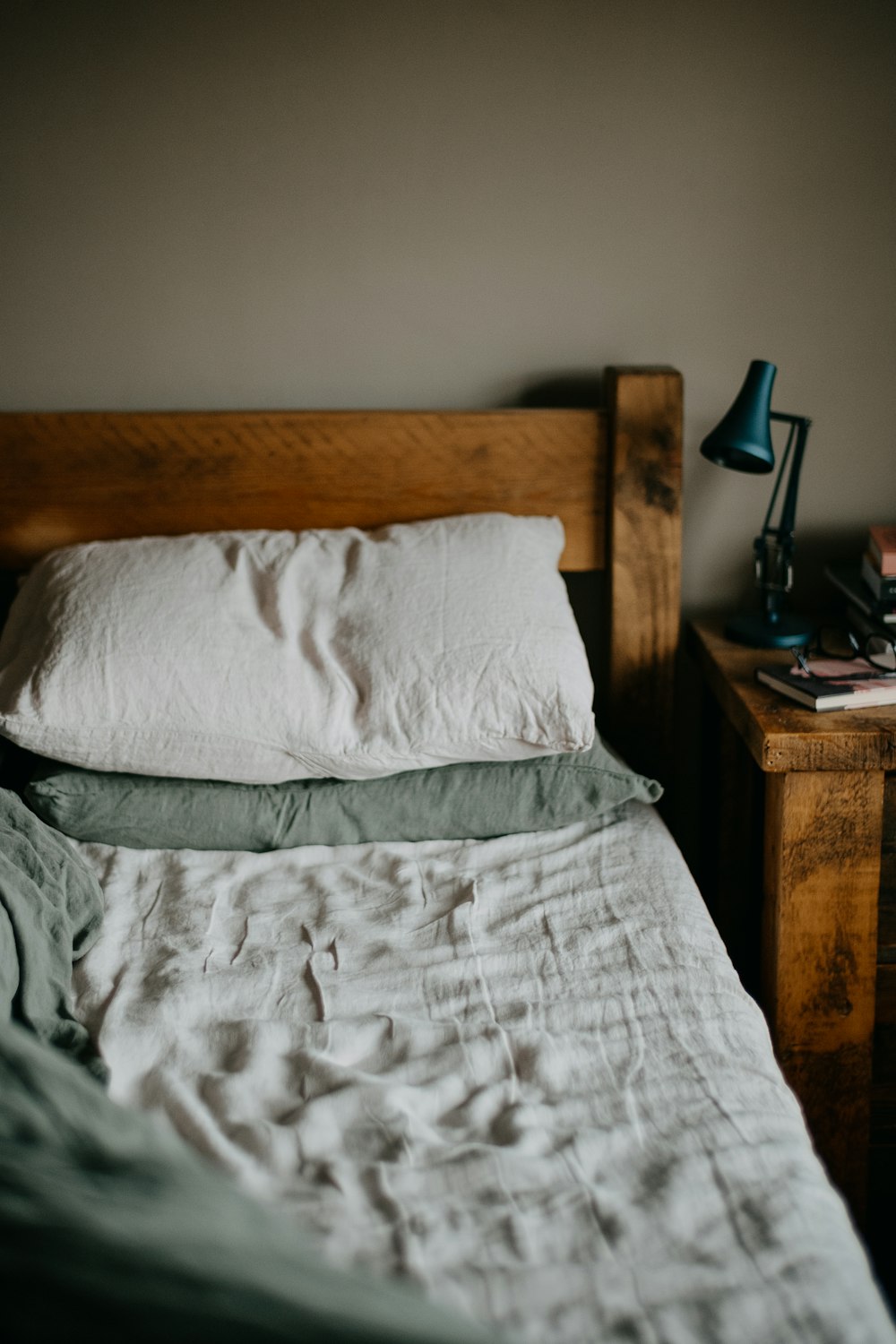un lit avec une couette blanche et une tête de lit en bois