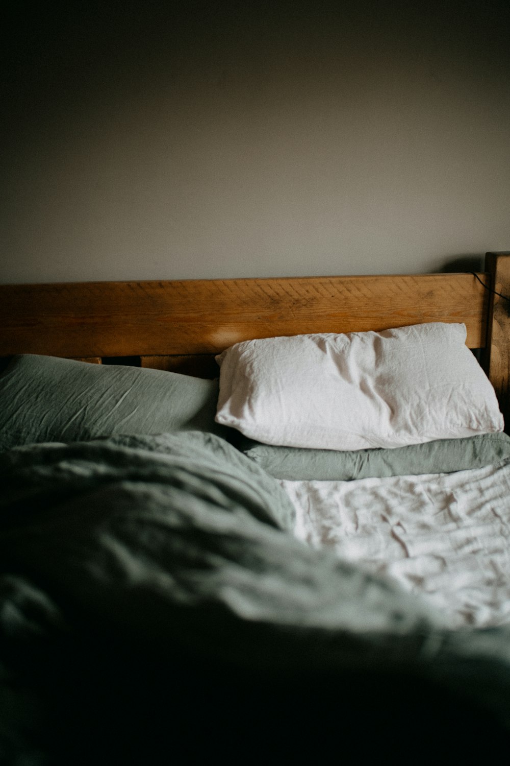 an unmade bed with a wooden head board