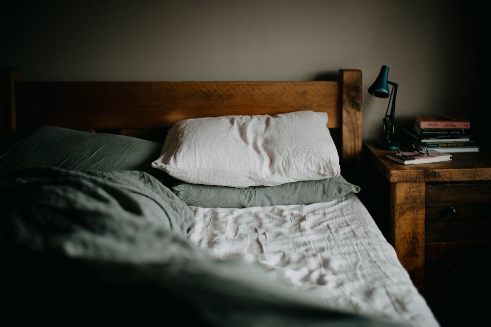 una cama con cabecera de madera y una mesita de noche