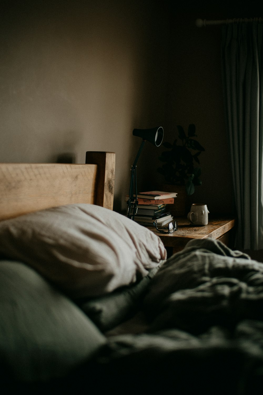 a bed with a wooden head board next to a window