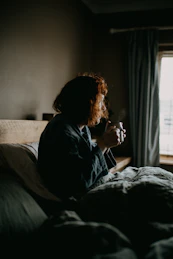a woman sitting on a bed in a dark room