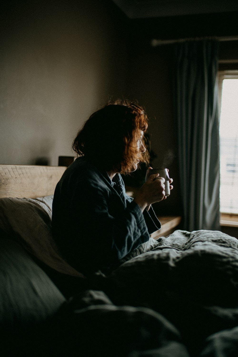 a woman sitting on a bed in a dark room