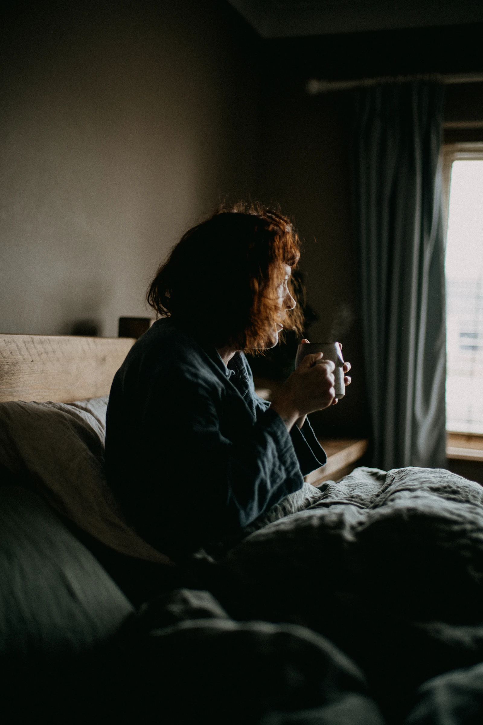 A woman sitting up awake in bed in a dark room at night