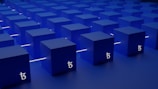 A series of blue cubes are arranged in a neat, orderly grid pattern on a flat surface. Each cube has a white symbol resembling a stylized 'T' on its side, likely representing a brand or logo. The cubes are illuminated from below with a soft glow, and white lines run between them, creating a sense of connectivity.