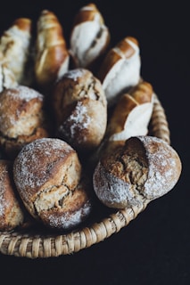 Freshly baked rolls arranged in a rustic basket on a wooden table outdoors.