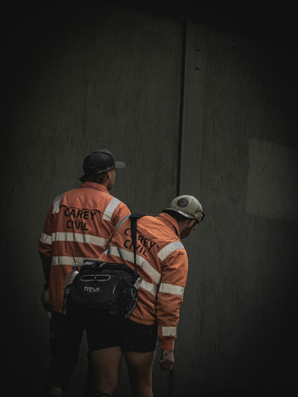 two men in orange jackets standing next to each other