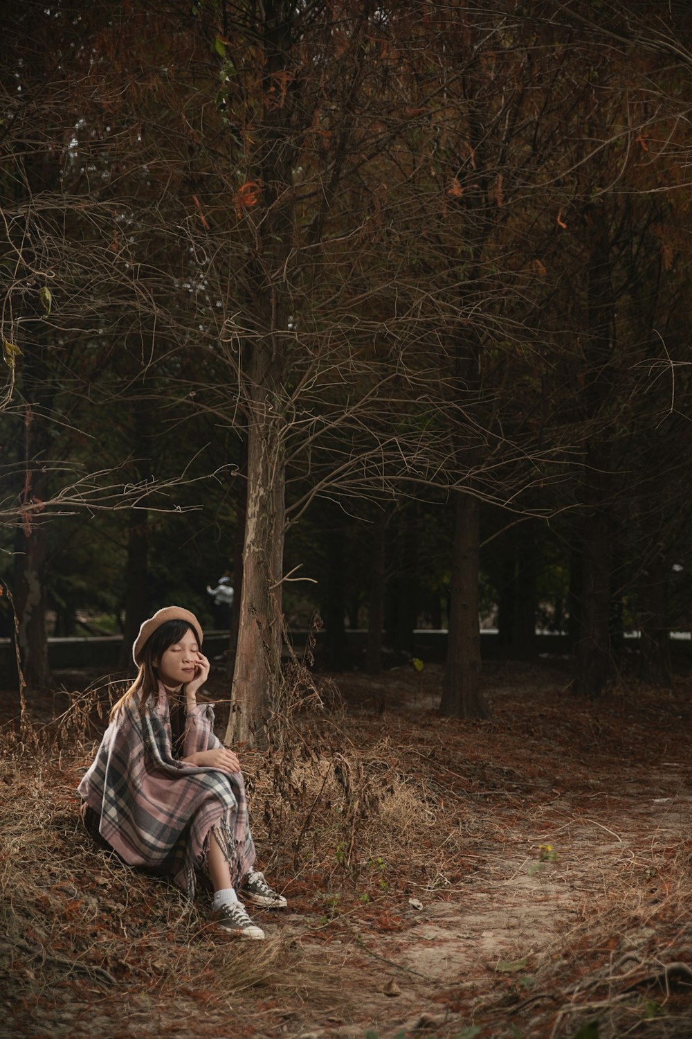 a woman sitting on the ground next to a tree