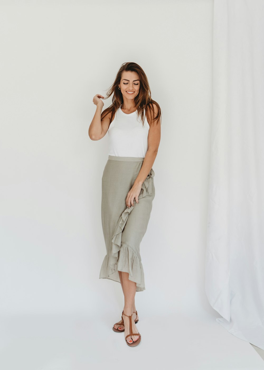 a woman in a white tank top and a gray skirt