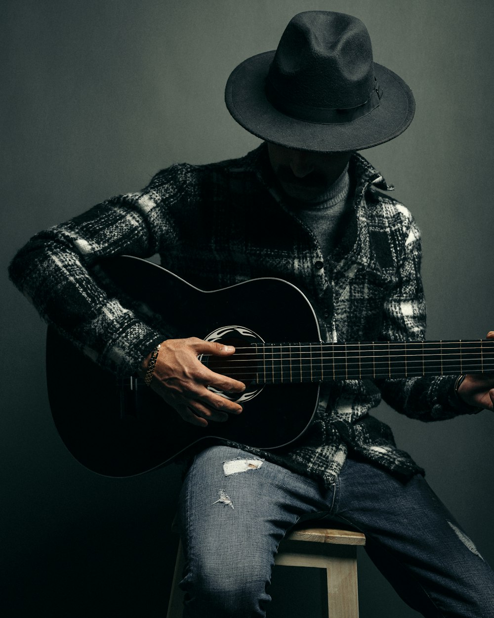 a man sitting on a stool playing a guitar