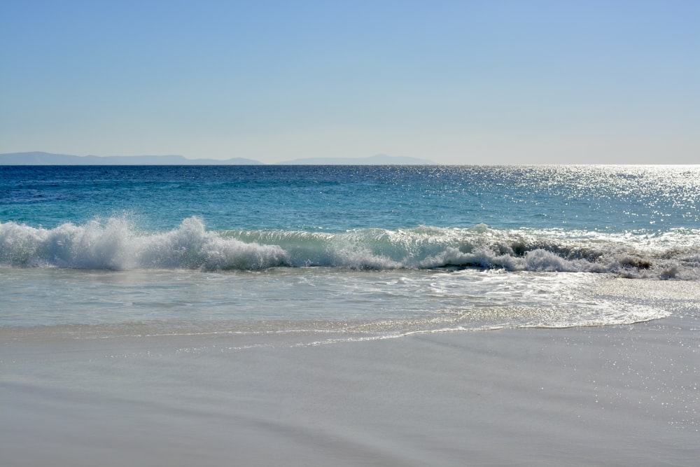 a beach with a wave coming in to shore