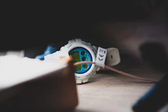 A stylish digital watch resting on a wooden table with soft lighting.