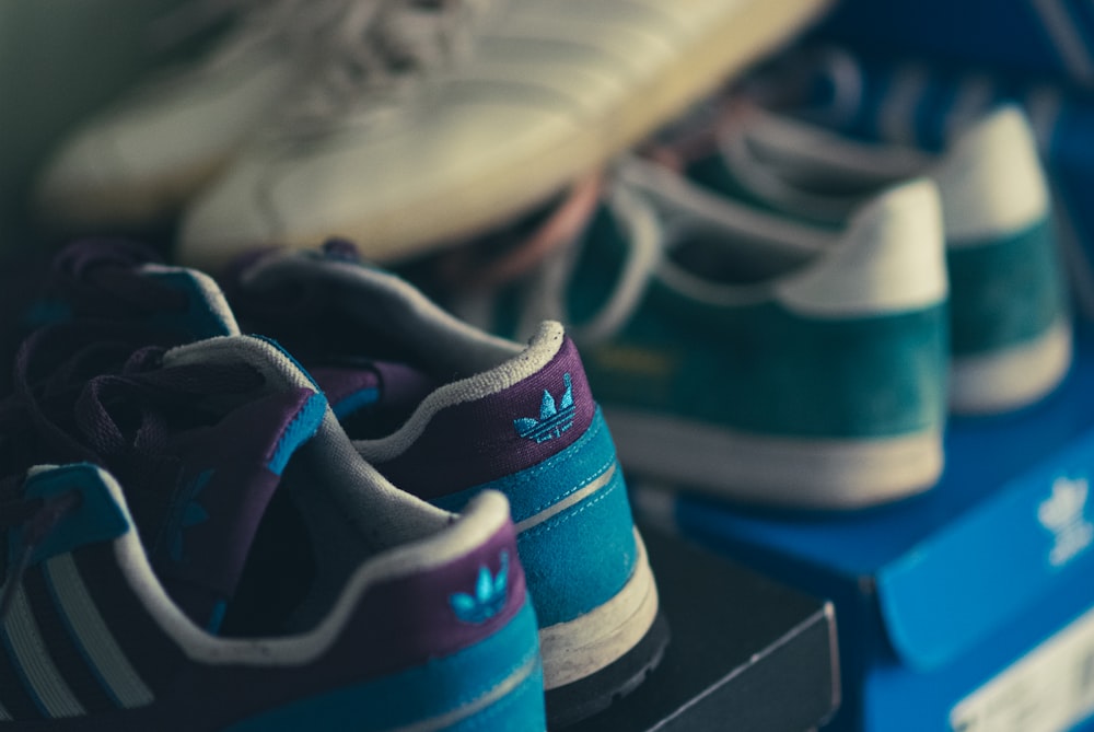 a row of adidas shoes sitting on top of a blue shelf