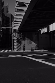 An evocative street scene at twilight showing a lone pedestrian and the interplay of shadows on worn pavement.