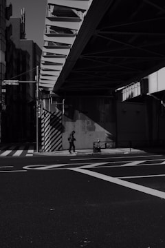 An evocative street scene at twilight showing a lone pedestrian and the interplay of shadows on worn pavement.