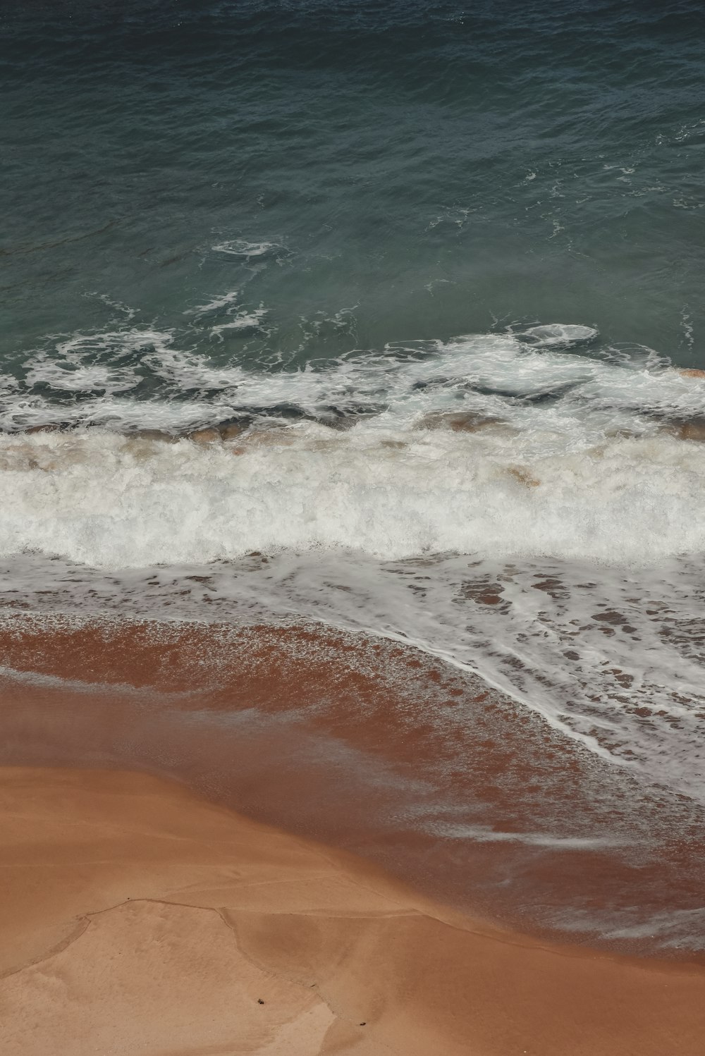 a man riding a surfboard on top of a wave covered beach