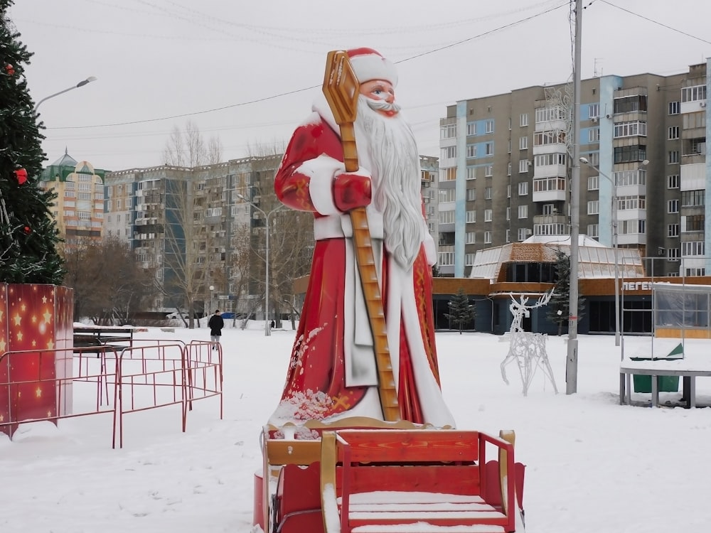 uma estátua de um Papai Noel segurando um trenó na neve