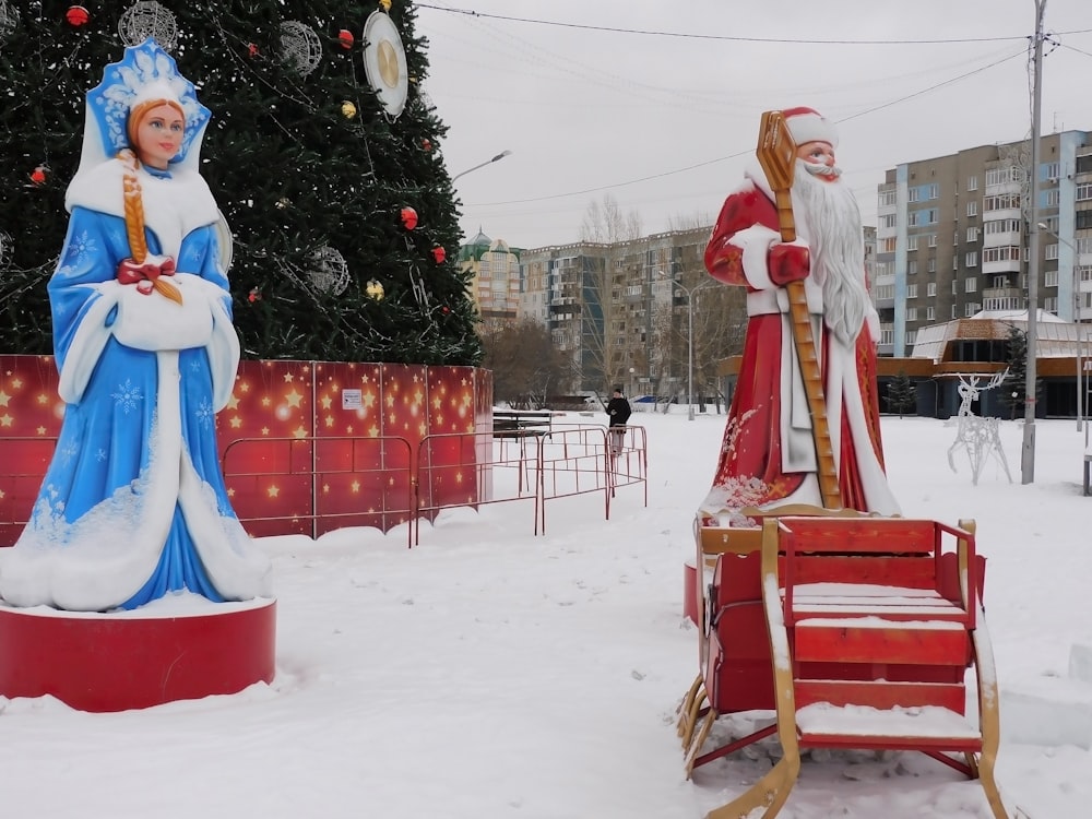 a statue of a woman and a man in front of a christmas tree