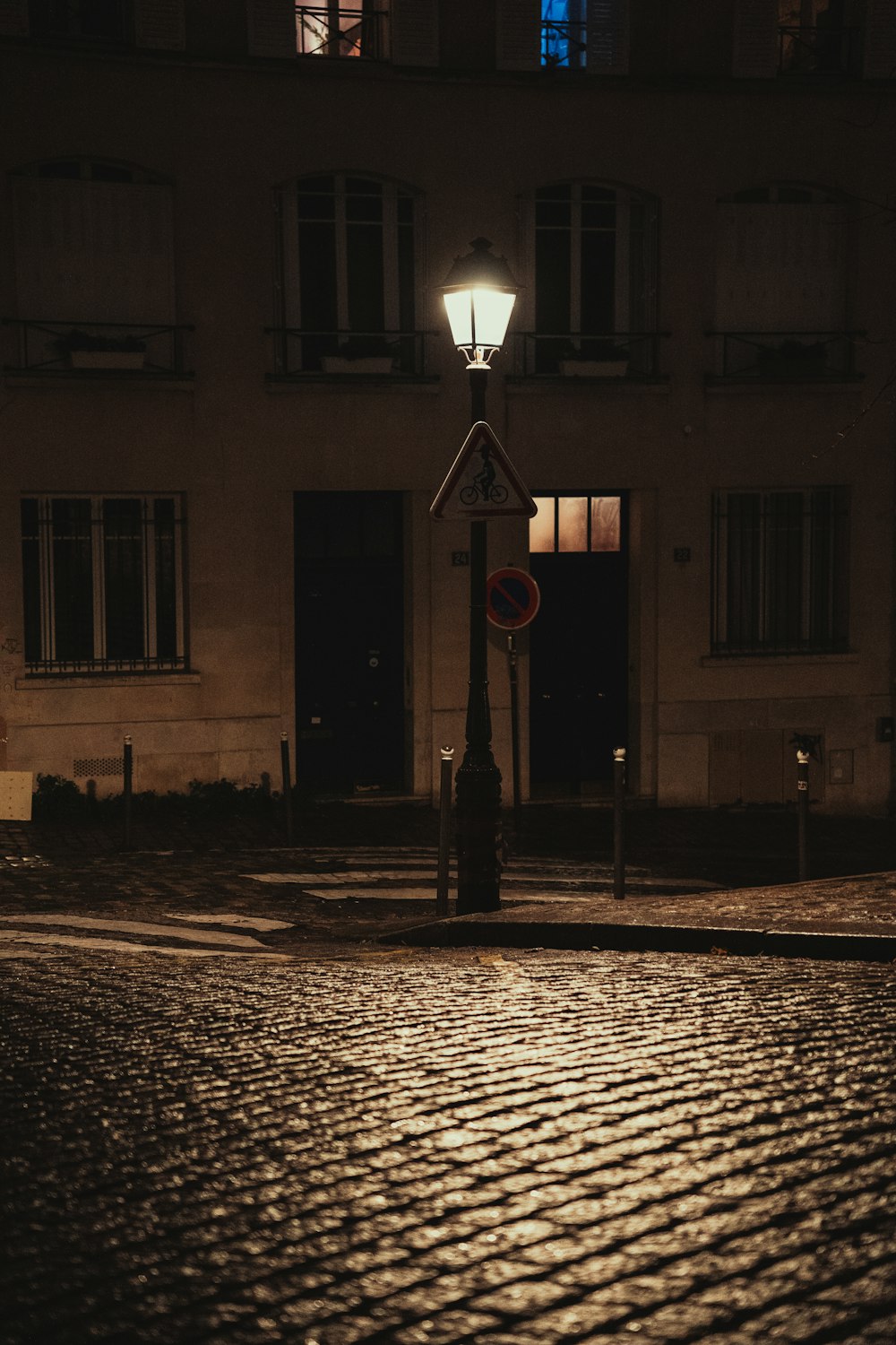 a street sign on a cobblestone street at night