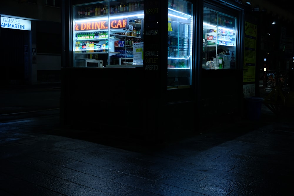 Una calle oscura por la noche con el frente de una tienda iluminada