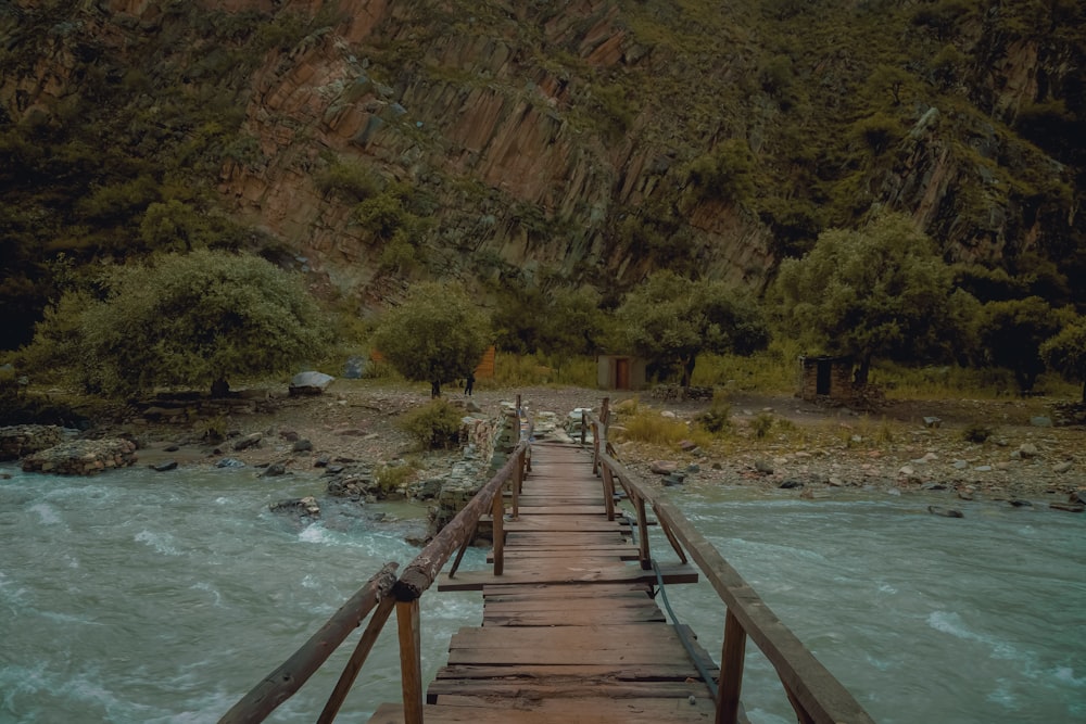 a wooden bridge over a river with a mountain in the background