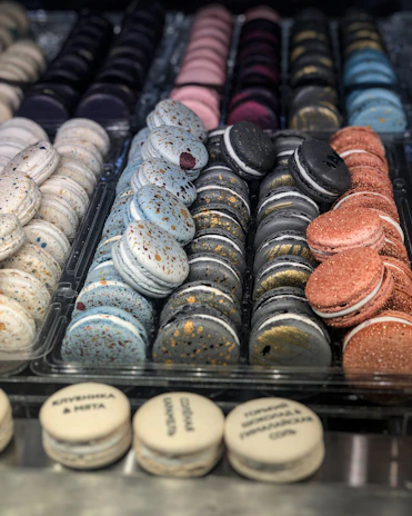 A vibrant assortment of colorful macarons arranged neatly on a sleek black slate.