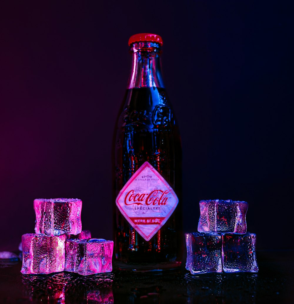 a bottle of coca cola sitting next to ice cubes
