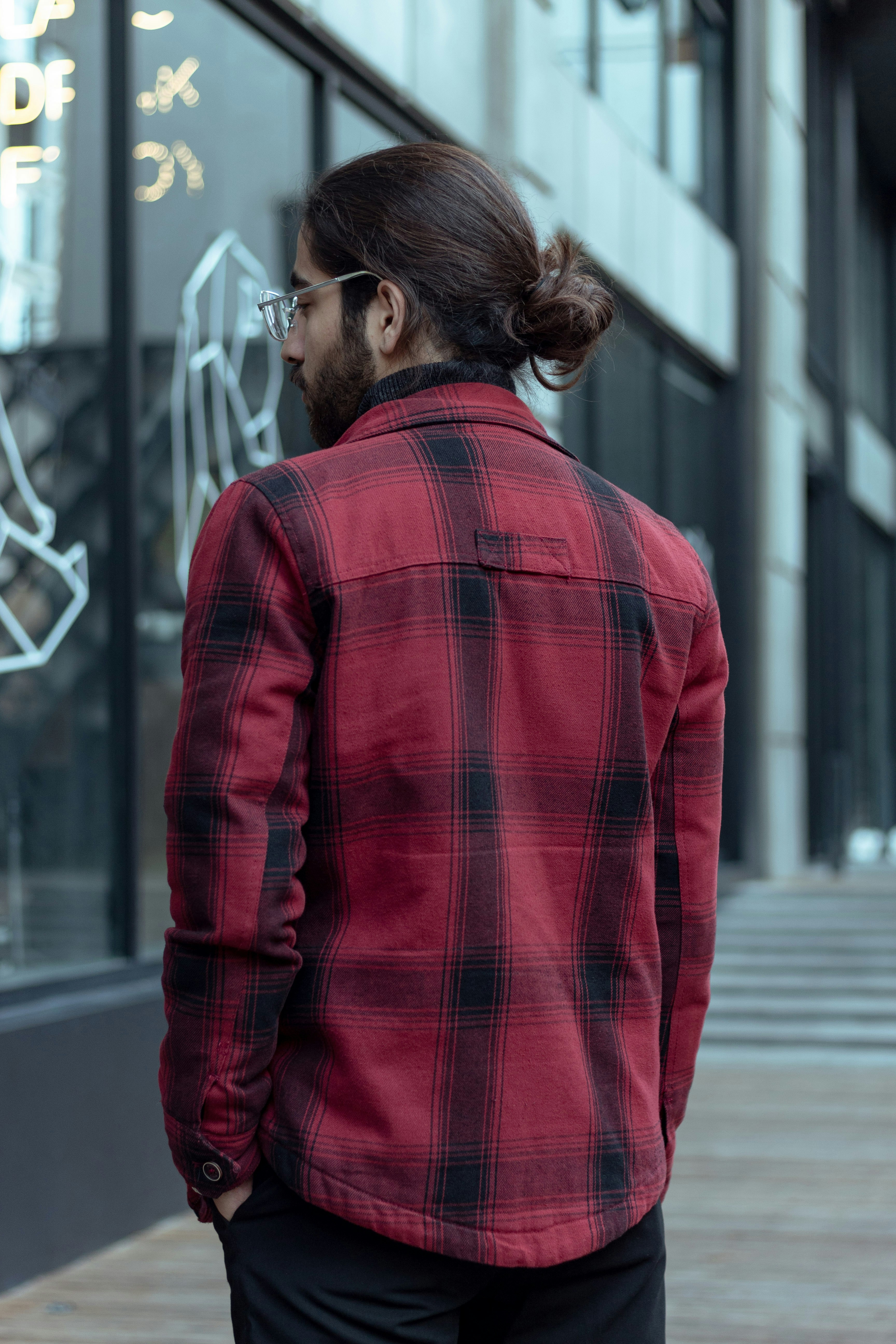 a man with a ponytail standing in front of a building