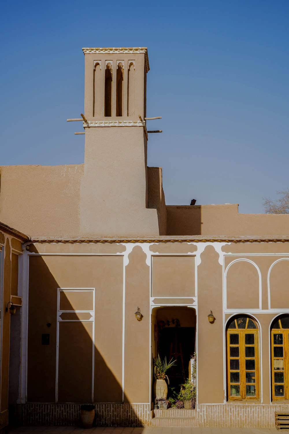 a tan building with a yellow door and a clock tower