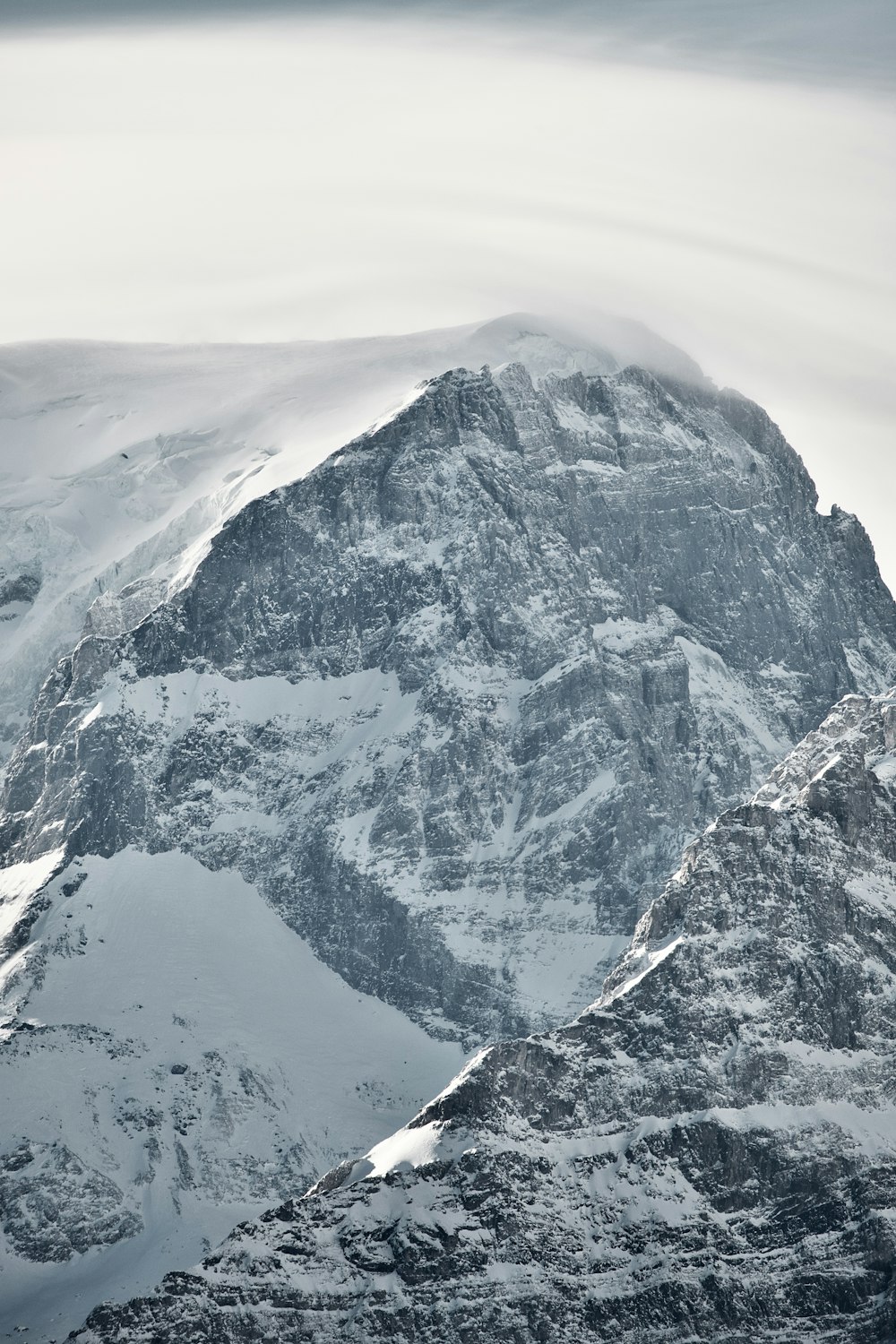 a large mountain covered in snow under a cloudy sky