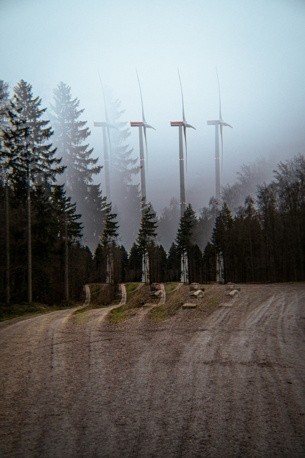 a dirt road with a bunch of wind mills in the background