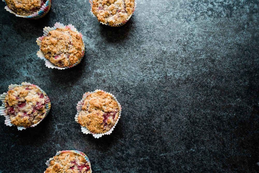 several muffins with crumbs on a black surface