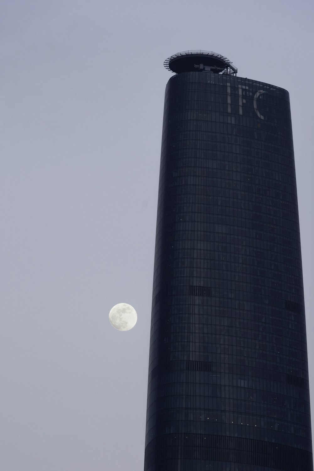 a very tall building with a very large moon in the sky