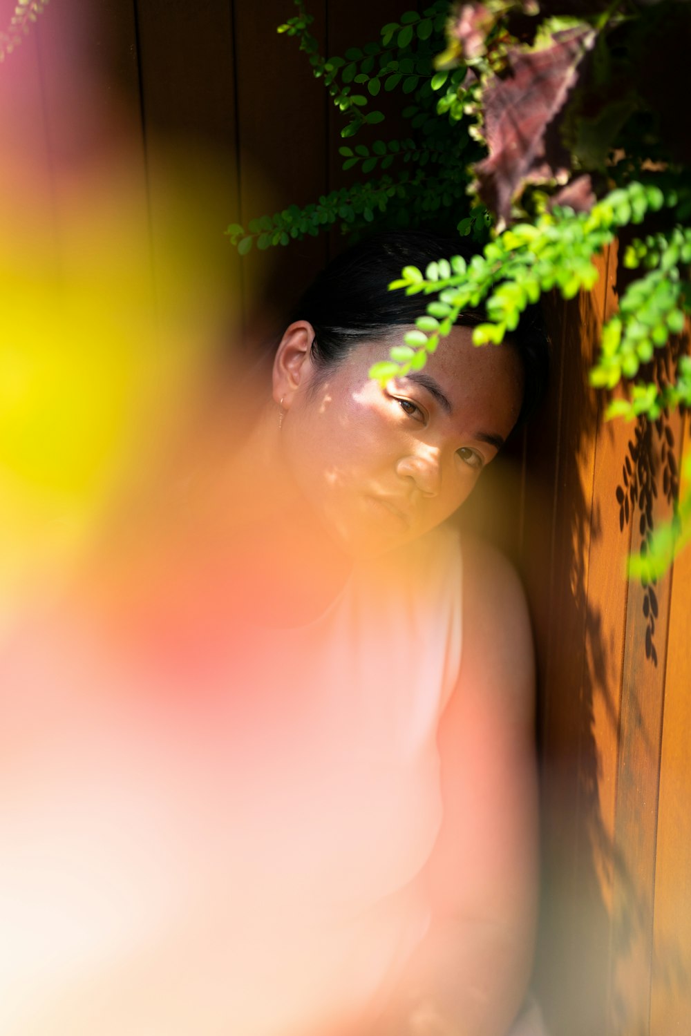 a woman sitting on a bench next to a plant