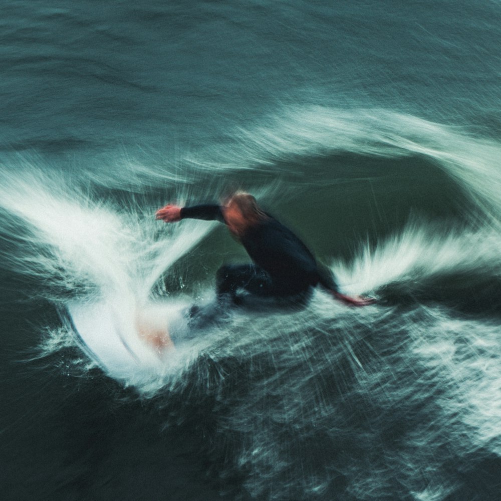 um homem cavalgando uma onda em cima de uma prancha de surf