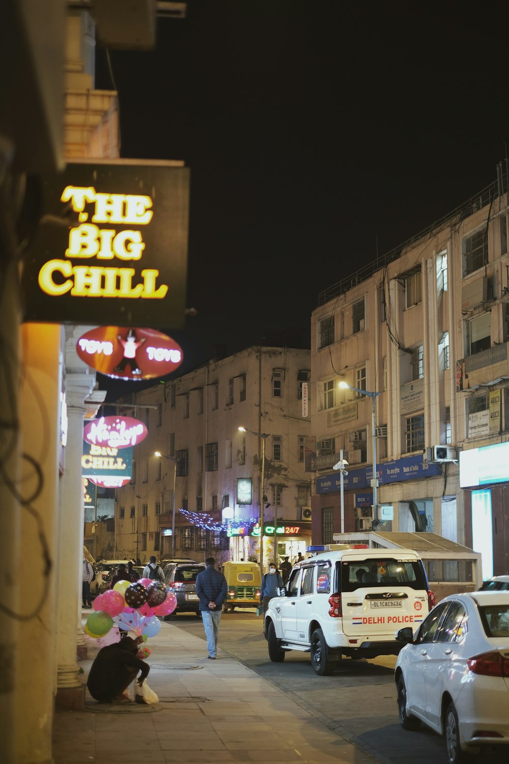 a busy city street at night with cars parked on the side of the road