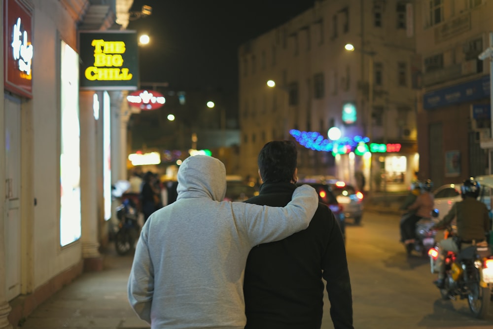 two people walking down a street at night