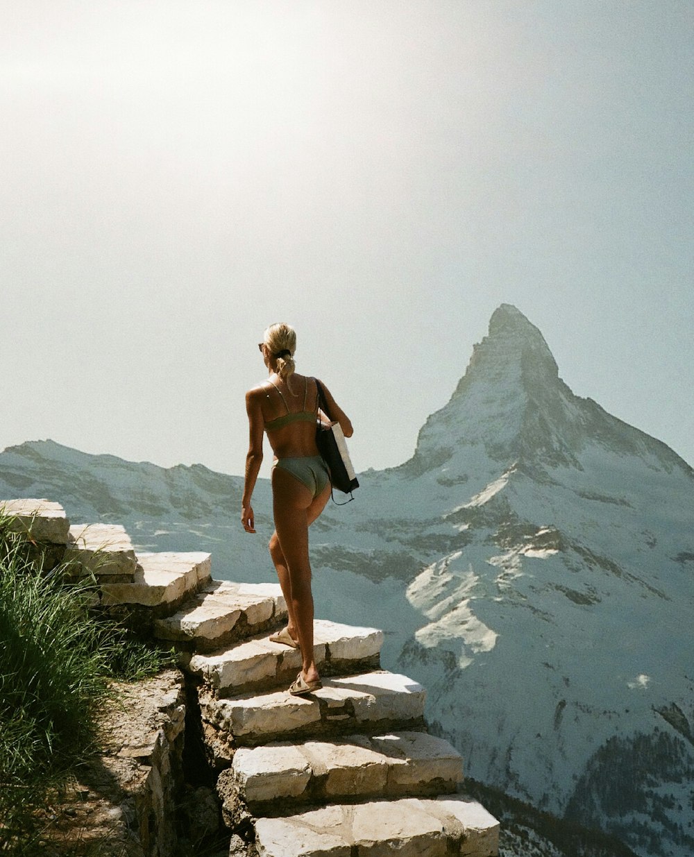 a woman in a bikini walking up a rocky path