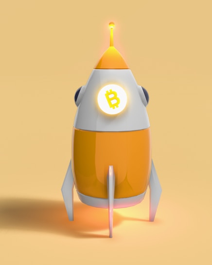 A stylized, futuristic rocket with an orange and white color scheme, featuring the Bitcoin symbol prominently displayed on its front. The rocket is set against a matching orange background, with light illuminating from its top and base, creating a glowing effect.