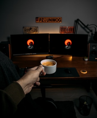 Wide-angle shot of Aldo Souza’s workspace featuring dual monitors and a coffee mug.