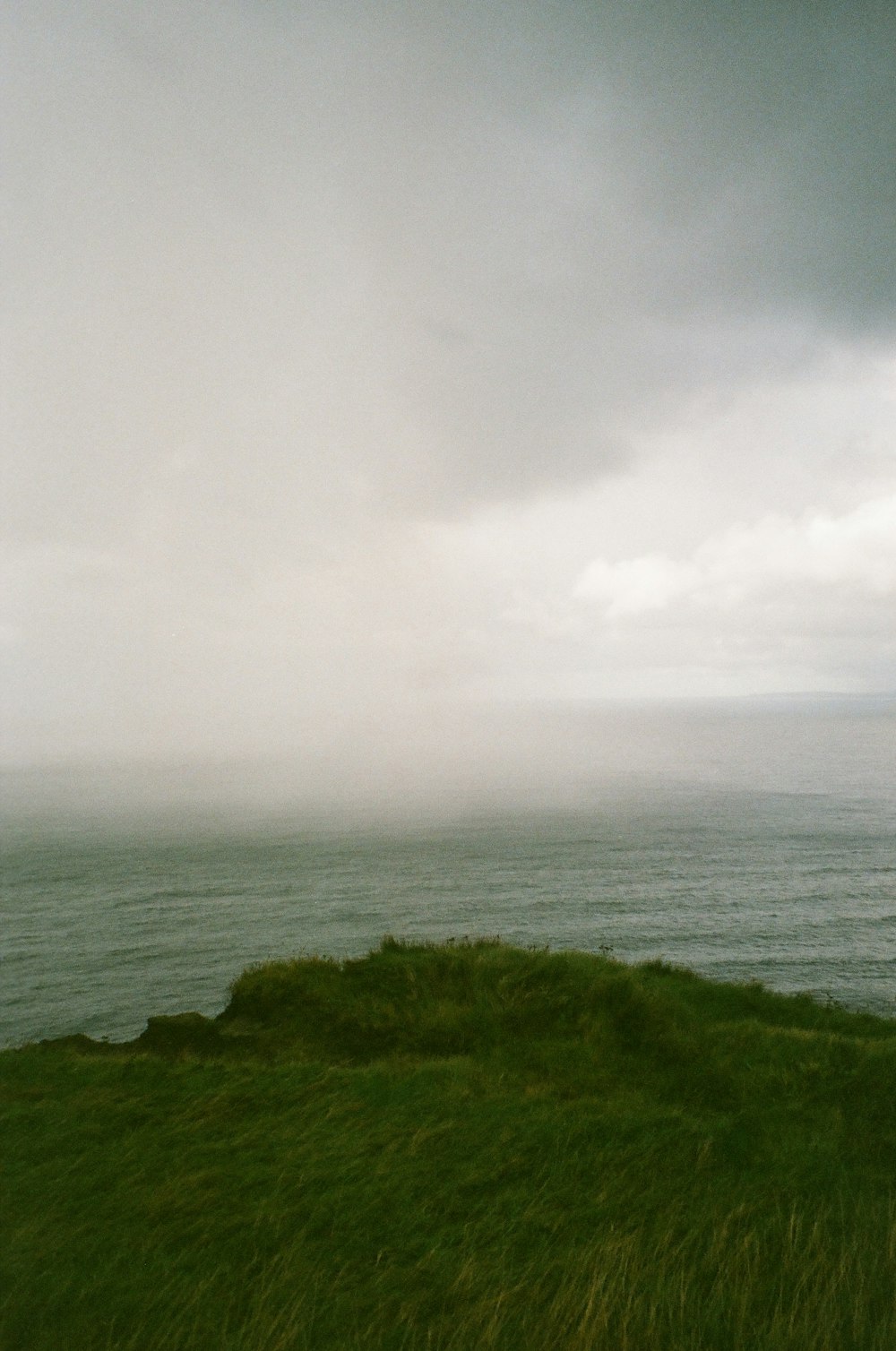 a grassy hill with a body of water in the background