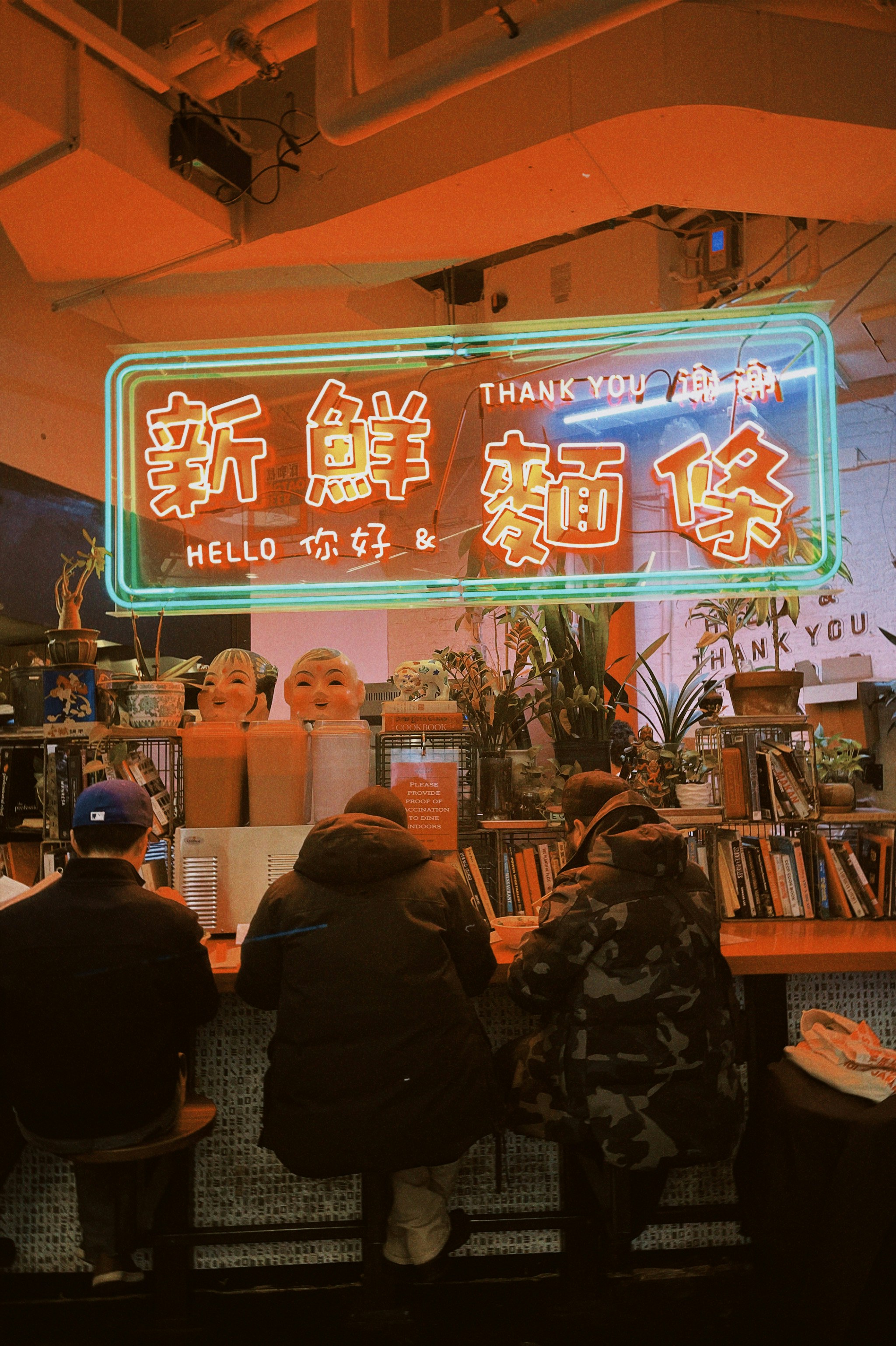 a group of people sitting at a table in front of a neon sign