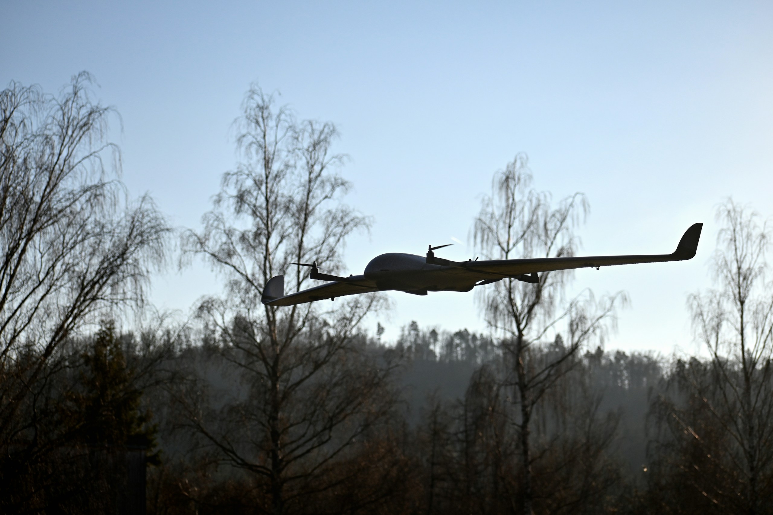 A DeltaQuad Pro VTOL UAV #map drone flying in front of four birch trees.