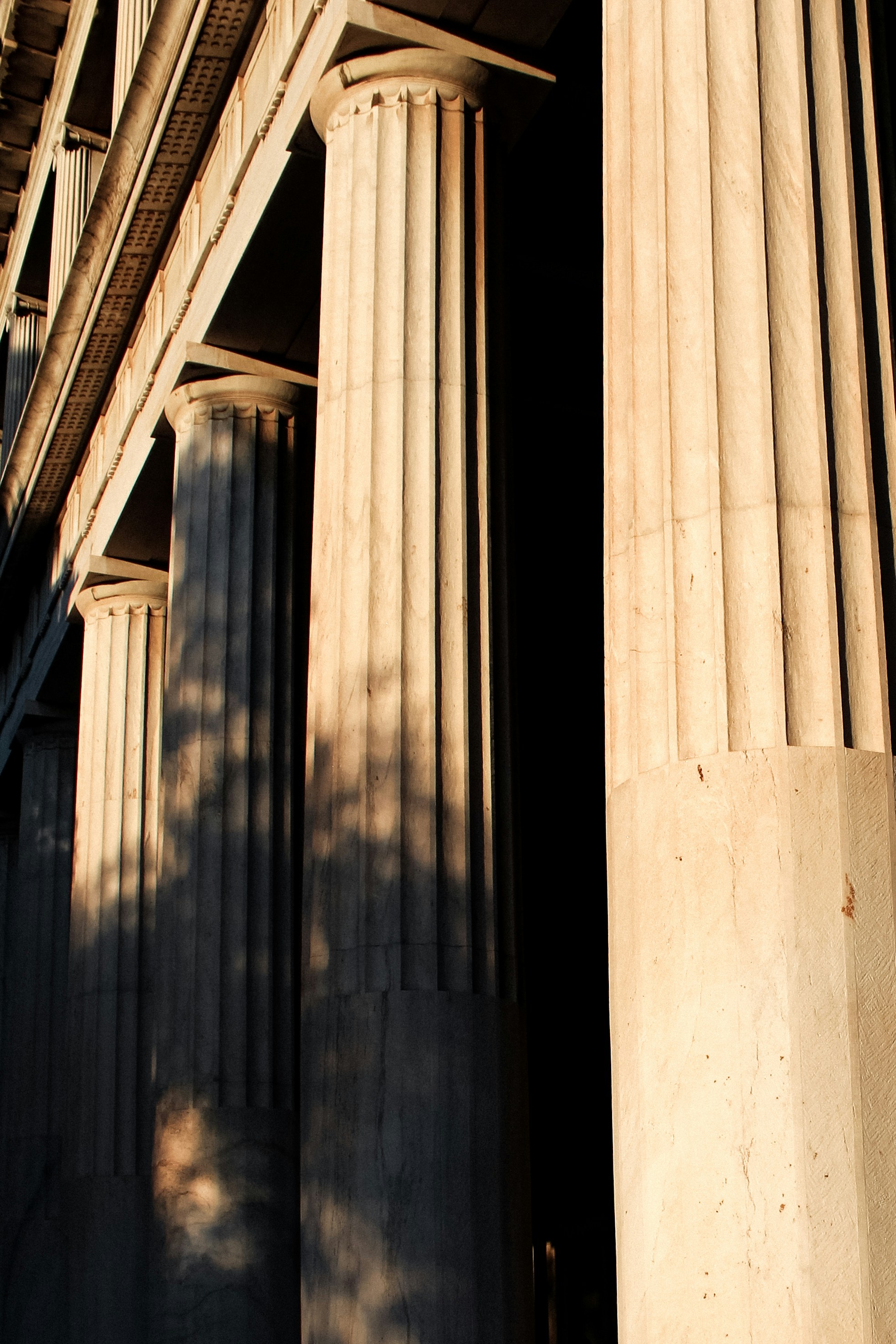 Ancient marble columns and stone textures in dim atmospheric lighting, classical architecture in shadow