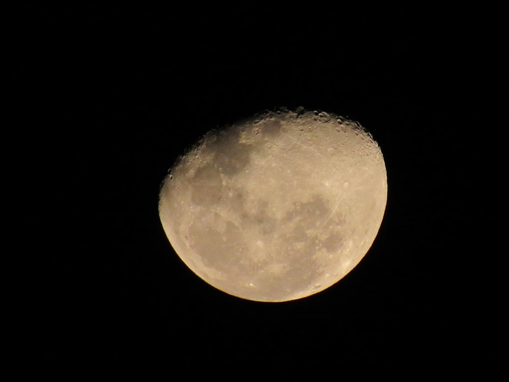 a full moon is seen in the dark sky