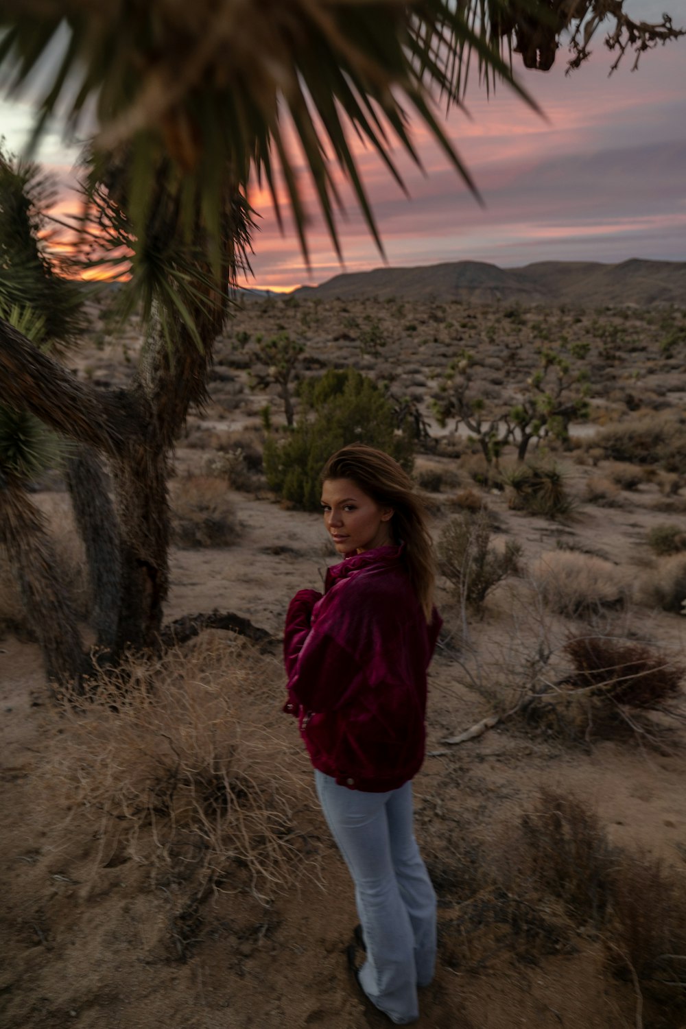 a woman in a red jacket standing in a desert